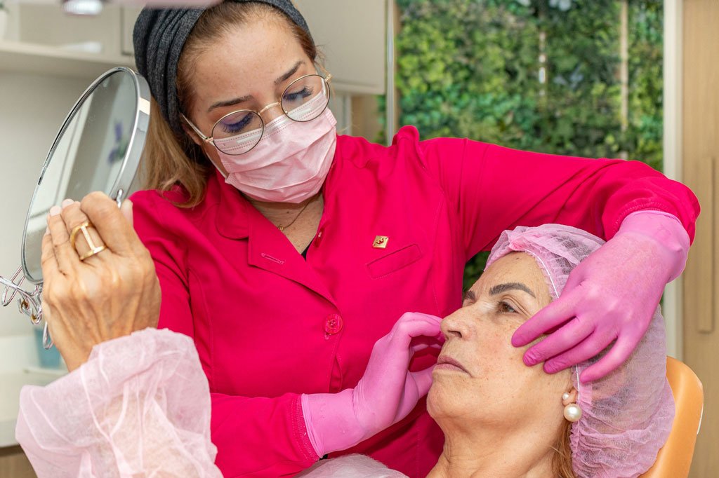 Dra. Analía King atendendo uma paciente que se olha no espelho para avaliar resultado, no consultório